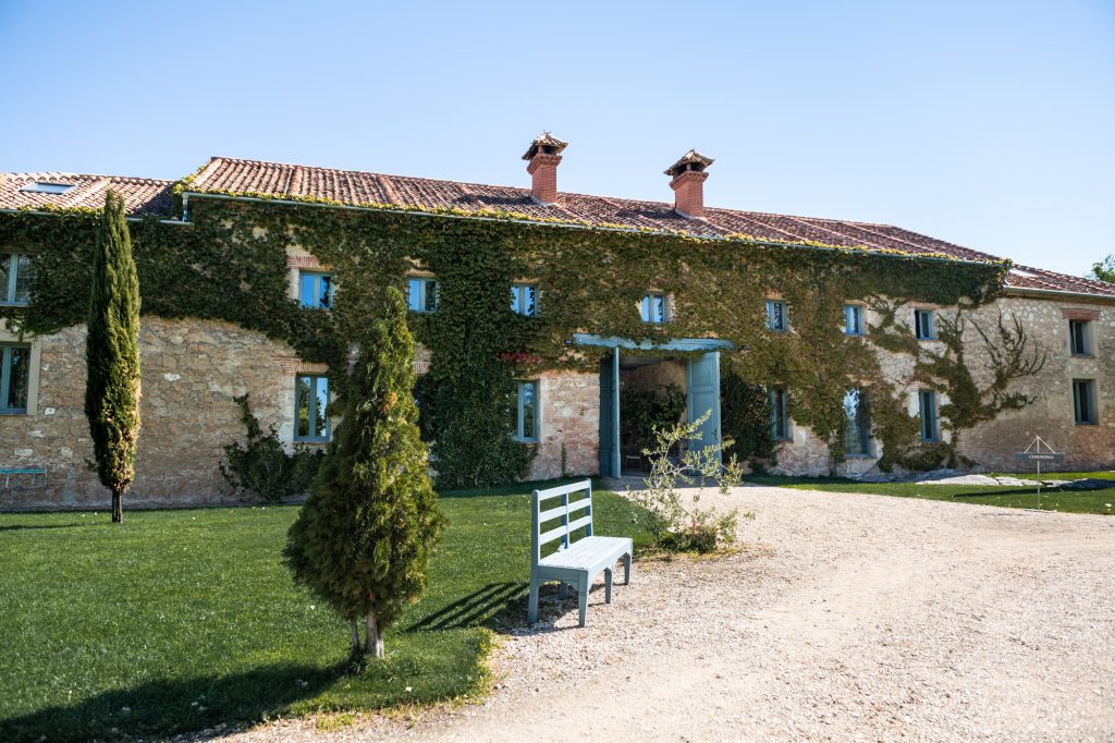 Las Margas es un refugio de piedra y luz en el corazón de Madrona (Segovia). Descubrimos la historia de esta casa de labor del siglo XIX y recorremos sus espacios desde una mirada pausada: desde la calma de sus jardines hasta la imponente arquitectura de su gran nave.